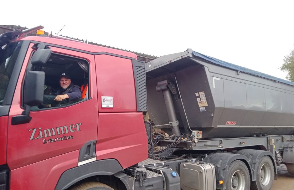 Lkw-Fahrer in einem roten Lkw mit einem schwarzen Anhänger.
