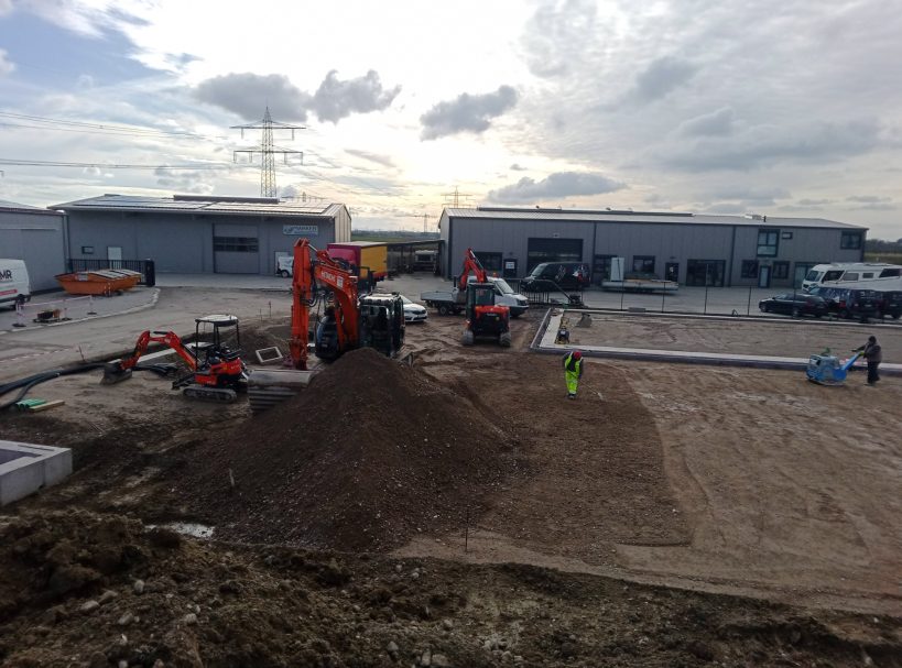 Baustelle mit Maschinen, Erde bewegt, und Arbeitern in einem Gewerbegebiet.